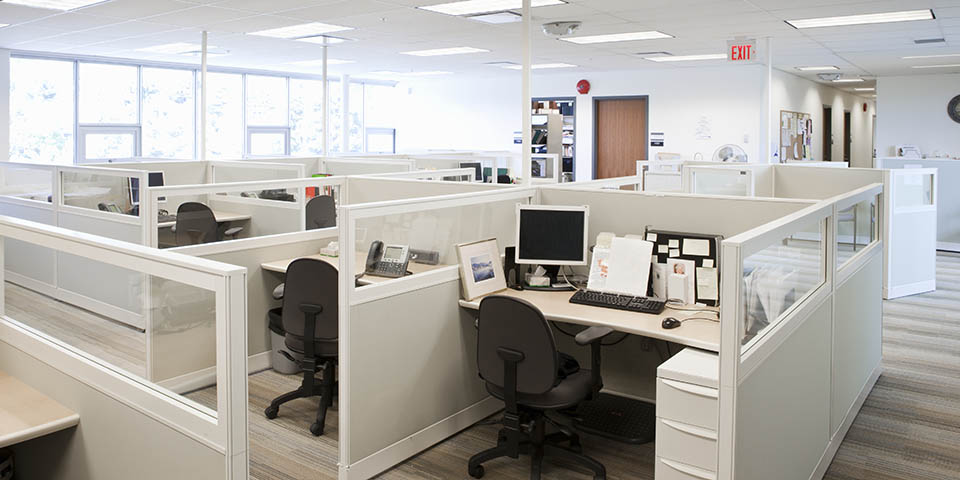 an interior of an office showing empty cubicle desks