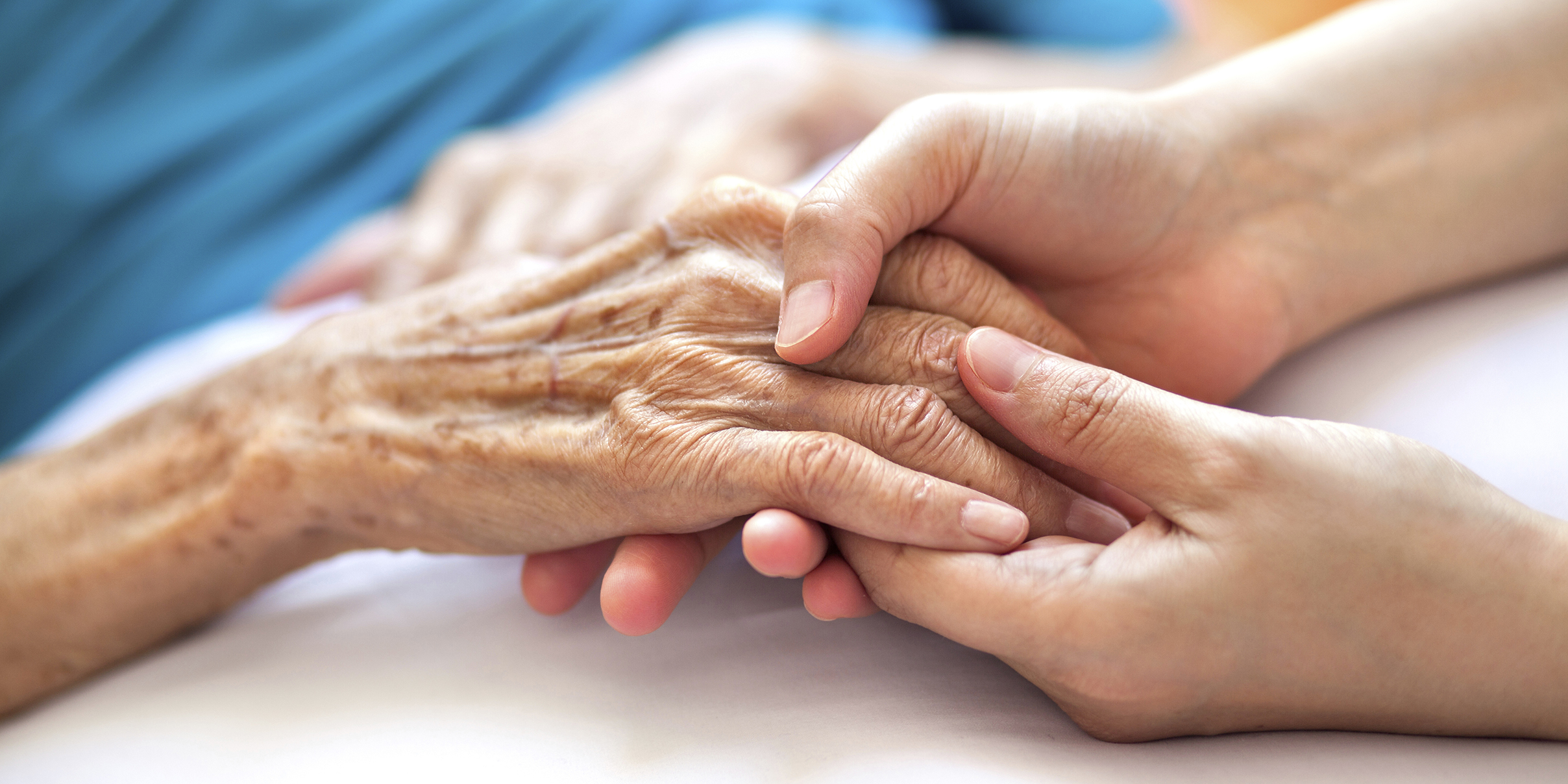 elderly woman holding hands with younger woman