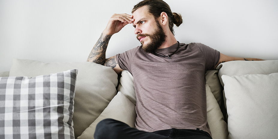 man sitting on a couch looking somber